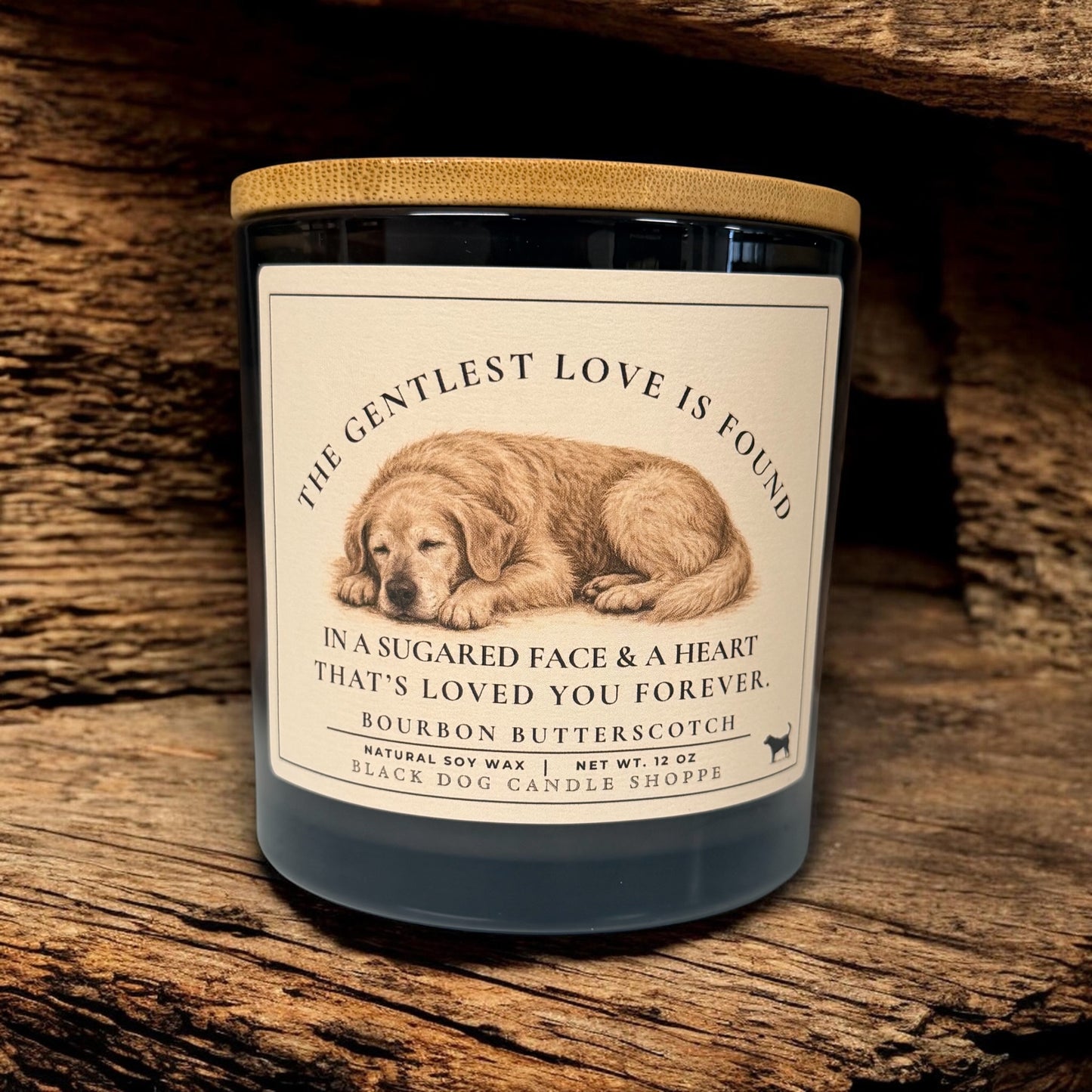 Dog sympathy soy candle in matte black jar with bamboo lid, featuring sleeping dog illustration and memorial message, styled on rustic wood background