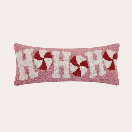 Decorative pillow with 'H' and candy cane pattern on a light pink background