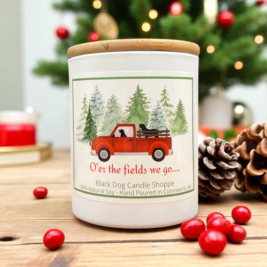 Candle with a red truck design on a wooden surface with Christmas decorations.