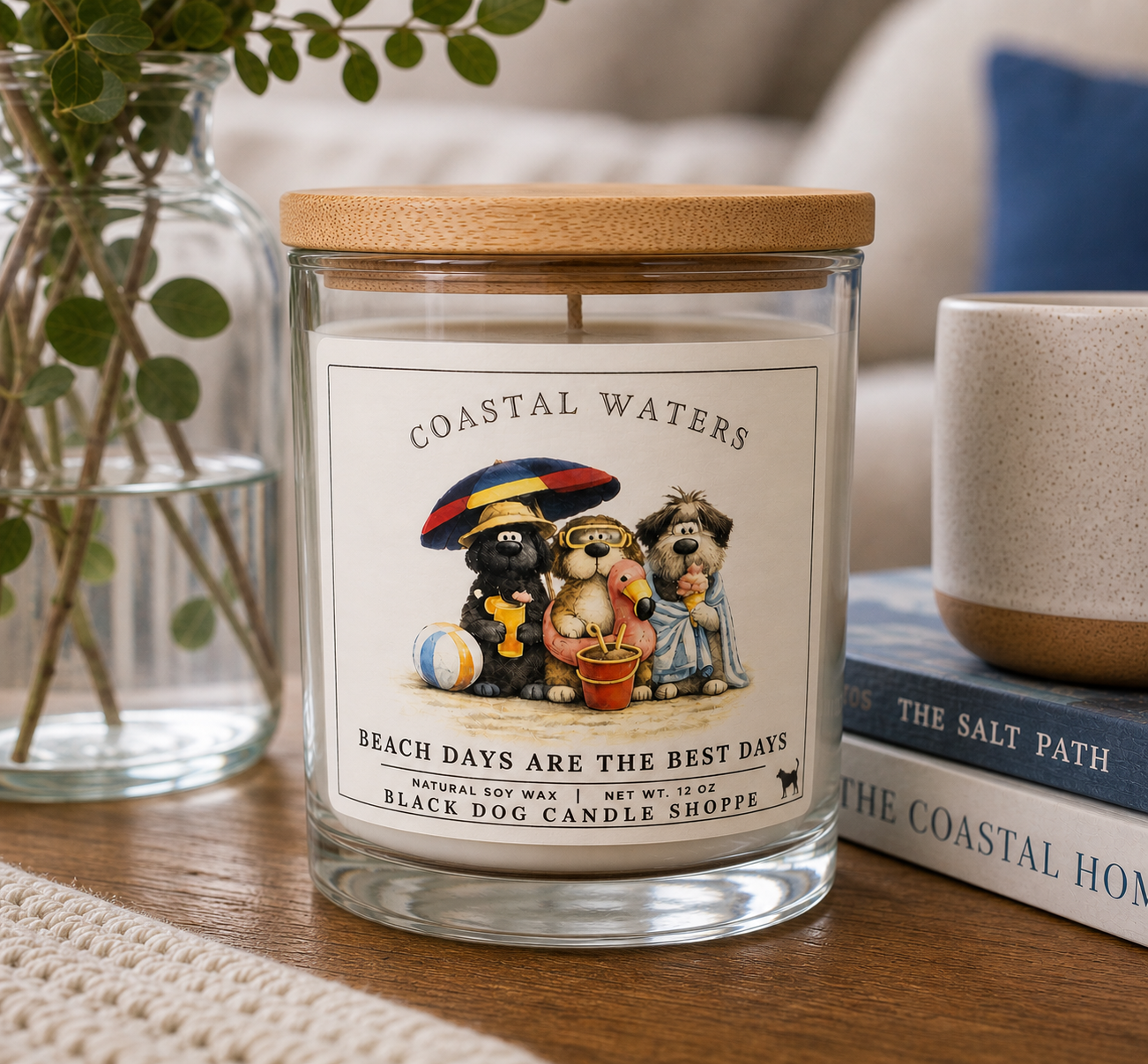 Coastal Waters soy candle in clear glass jar with bamboo lid, featuring dog beach illustration, styled on wooden table with books and greenery