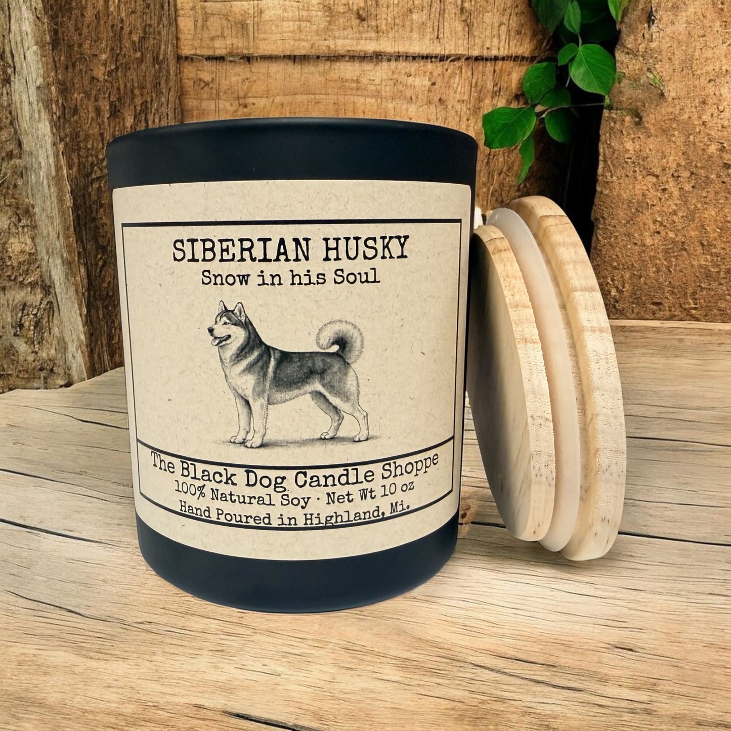 Siberian Husky soy candle in matte black jar with bamboo lid, featuring vintage husky illustration and “Snow in his Soul” label, styled on rustic wood background