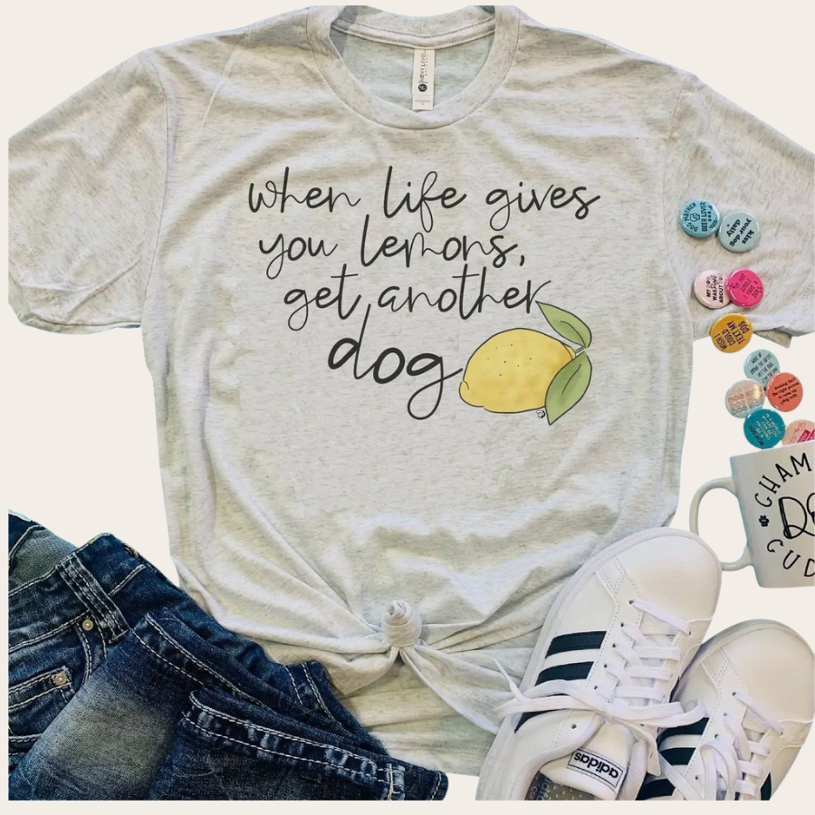 Light gray graphic t-shirt with “When life gives you lemons, get another dog” quote and lemon illustration, styled with jeans and sneakers
